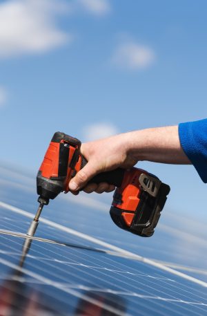 Close up view of engineer working with electric screwdriver drill installing solar panel